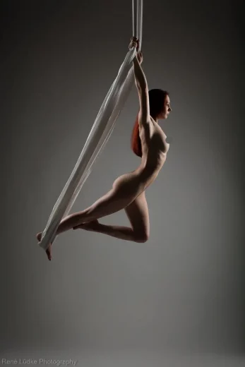 Bild einer nackten Frau die an einem Tuch von der Decke hängt