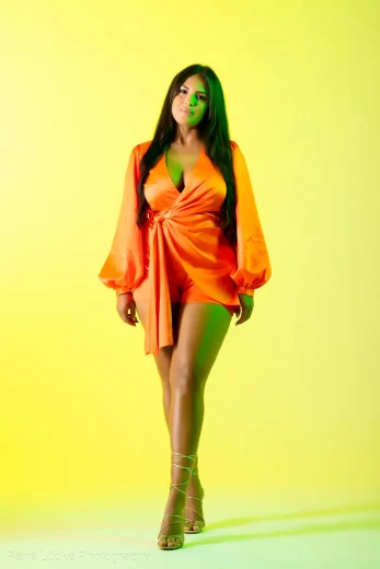 Fashionportrait einer stehenden Frau in einem orangen Outfit
